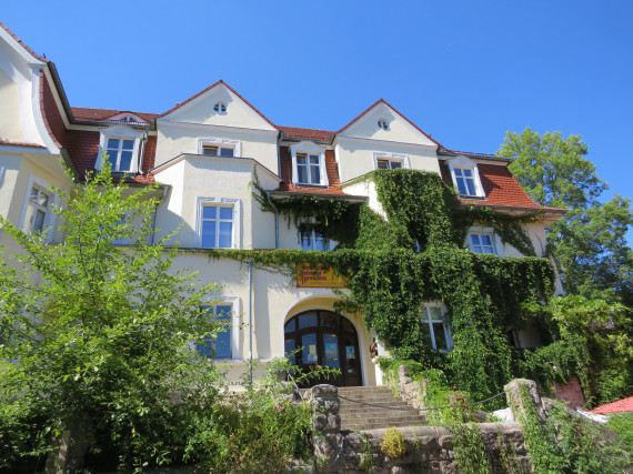 Die Jugendstilvilla &quot;Villa Füglein&quot;, in der sich das Deutsche Fahrradmuseum befindet, wurde im Jahr 1908 erbaut. Auf diesem Bild ist das Haus im Sommer zu sehen, mit grünem wildem Wein bewachsen, Bäumen im Vordergrund uns blauem Himmel im Hintergrund.
